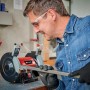 Smerigliatrice doppia Einhell TC-BG 150 in uso: uomo che smeriglia metallo con la smerigliatrice in officina.
