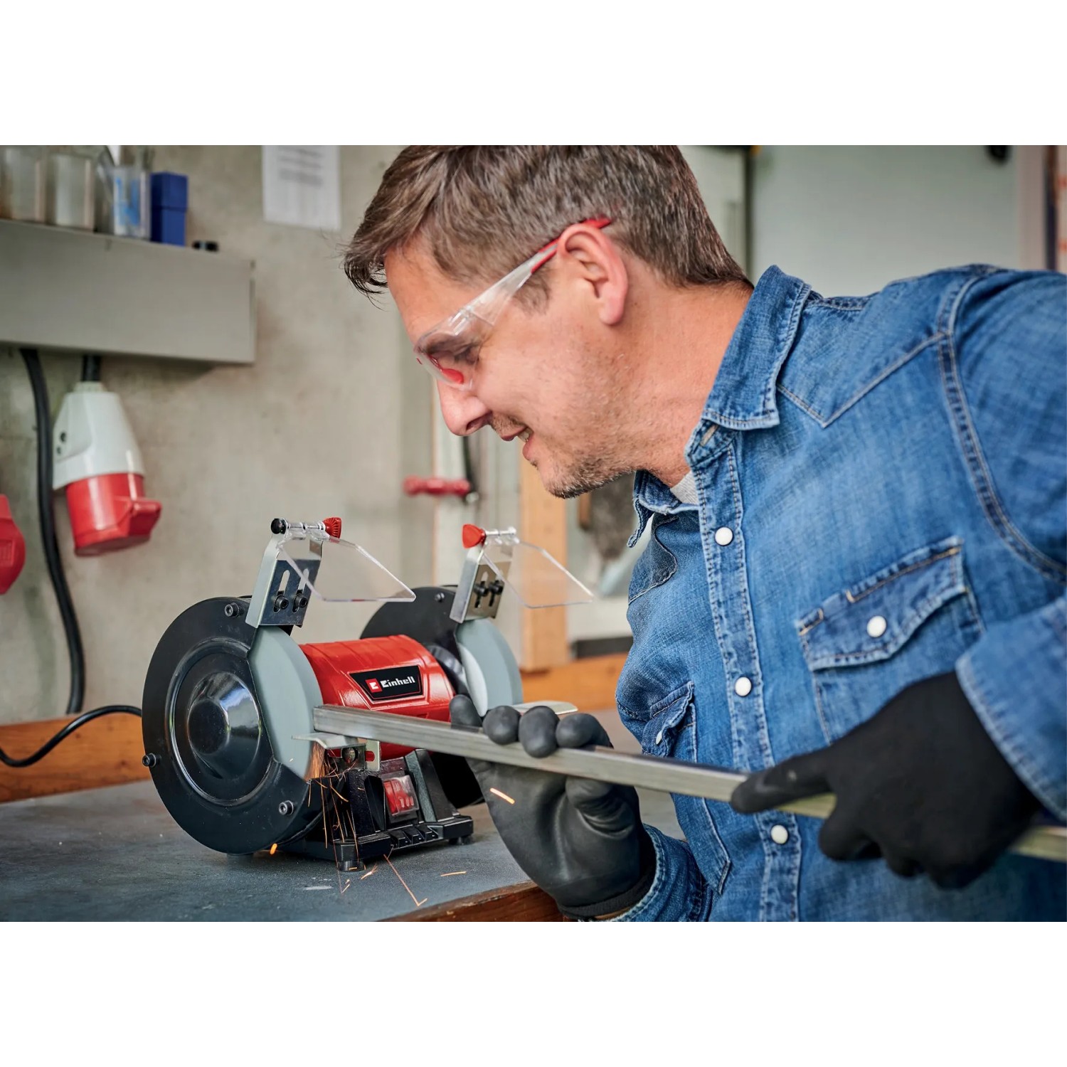Smerigliatrice doppia Einhell TC-BG 150 in uso: uomo che smeriglia metallo con la smerigliatrice in officina.
