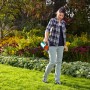 Donna che utilizza lo spargitore manuale Gardena Kleinstreuer S turchese in giardino per fertilizzare.