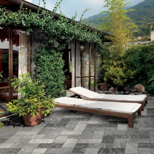 Pavimentazione esterna grigia t.b.t. con lettini e piante.