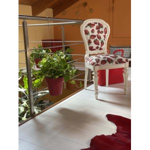Sedia decorativa con motivo a fragole e pianta pensile in vaso rosso.