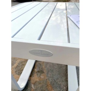Dettaglio di un tavolo da giardino bianco con superficie a listelli e struttura in metallo.