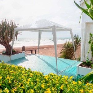 Gazebo t.b.t. bianco su una spiaggia con vista mare.