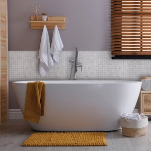 Bagno con piastrelle a mosaico grigie come decorazione murale, vasca e accenti gialli.