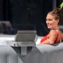 Vassoio Bestway LAY-Z-SPA fissato alla vasca idromassaggio con tablet e donna sullo sfondo.