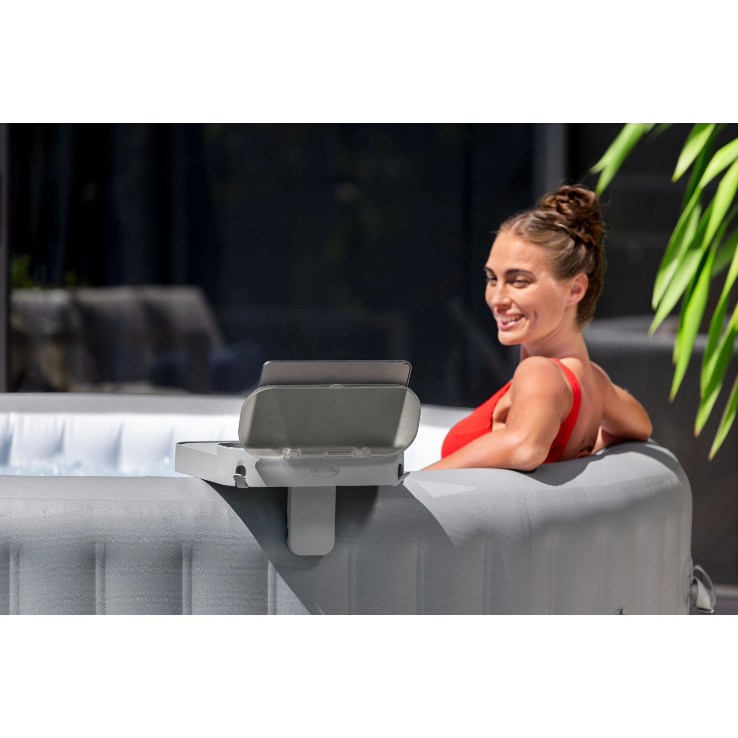 Vassoio Bestway LAY-Z-SPA fissato alla vasca idromassaggio con tablet e donna sullo sfondo.