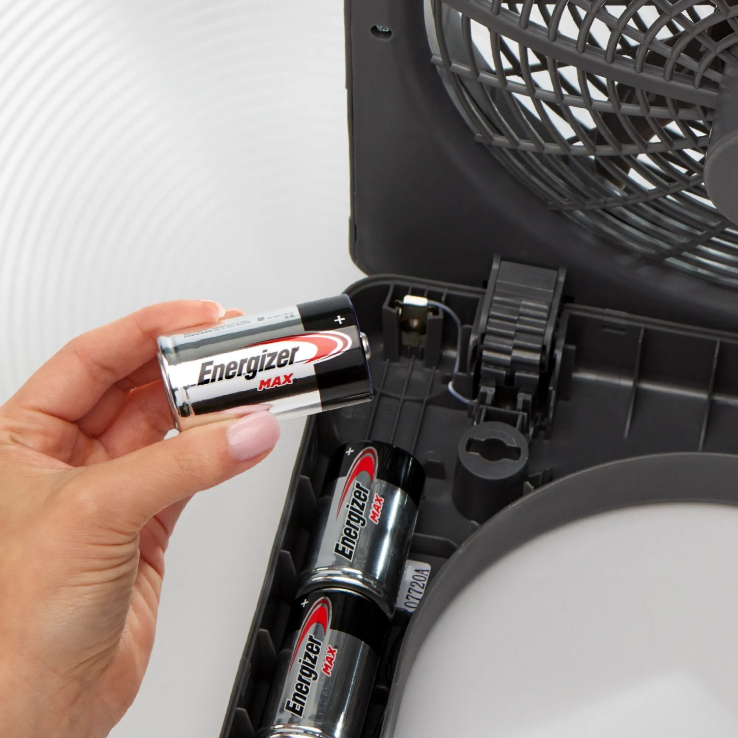 Una mano inserisce le batterie Energizer C Baby nel vano batterie di un ventilatore.