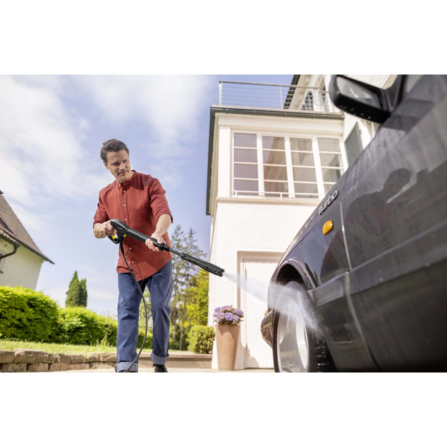 Uomo pulisce l'auto con idropulitrice. Ideale per giardino e cortile.