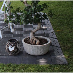 Piastrelle per patio scure posate come bordura con decorazione e bonsai in vaso.