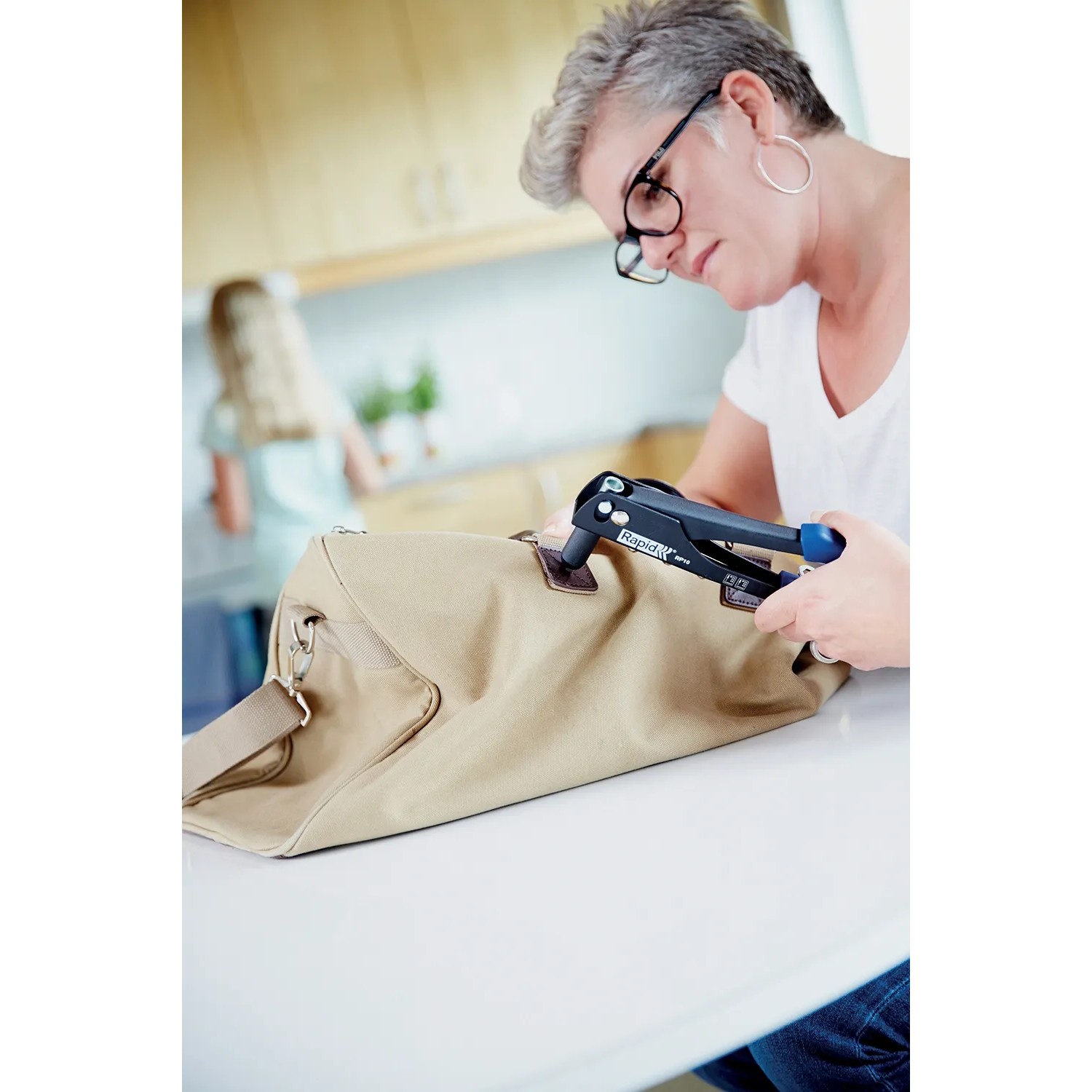 Donna utilizza la rivettatrice Rapid RP10 su una borsa. Include 100 rivetti.
