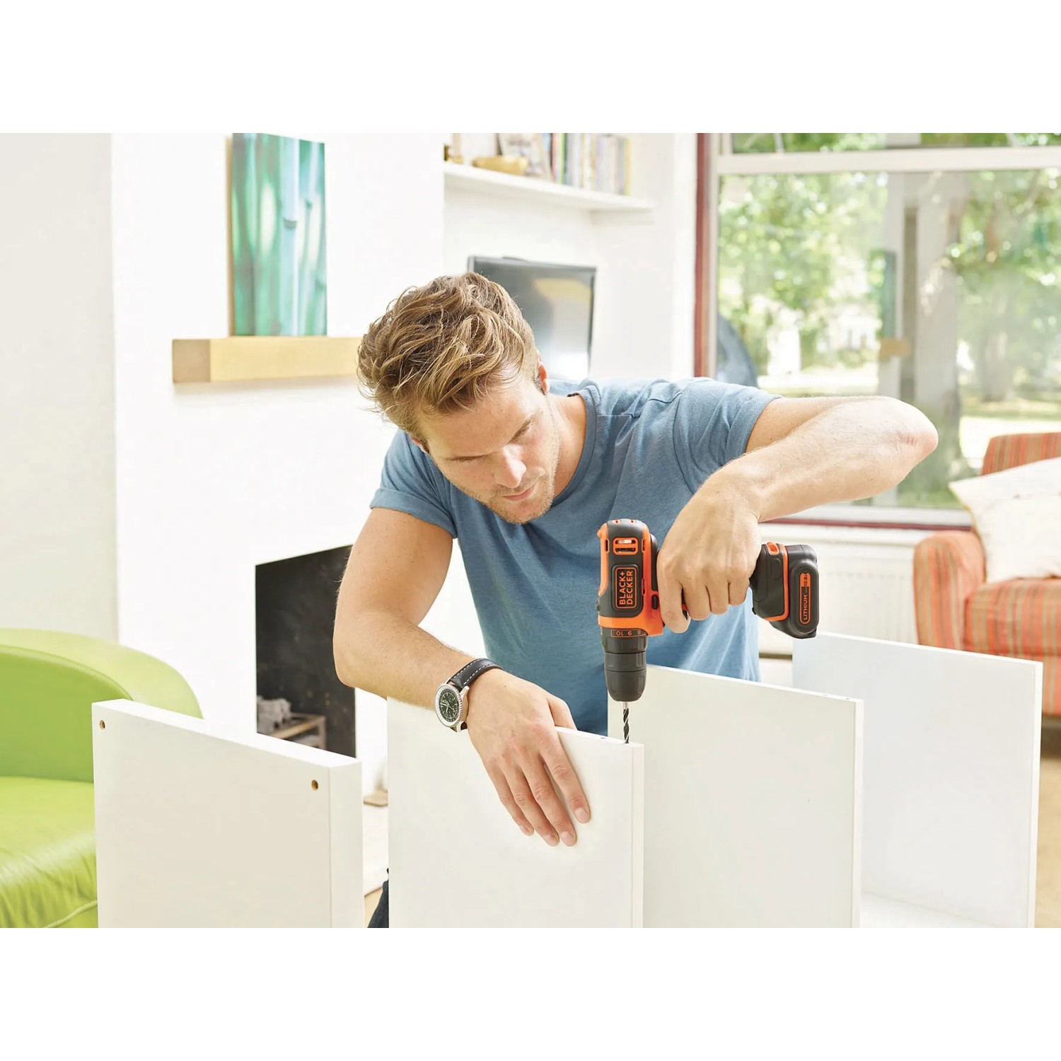 Uomo che assembla mobili con avvitatore a batteria Black+Decker. Avvitatore con batteria e custodia.
