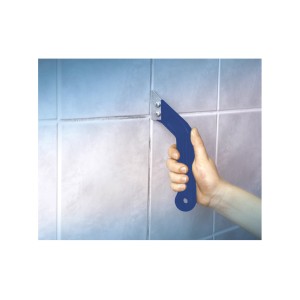 Mano che tiene il pulitore per fughe LUX in metallo duro Classic sulle piastrelle. Strumento per pulire le fughe delle piastrelle.