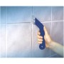Mano che tiene il pulitore per fughe LUX in metallo duro Classic sulle piastrelle. Strumento per pulire le fughe delle piastrelle.