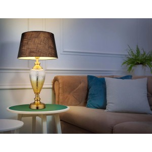 Elegante lampada da tavolo con paralume nero e base dorata su un tavolino.