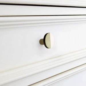 Pomello rotondo bicolore (oro/bianco) per mobile su cassetto bianco.