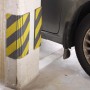 Protezione antiurto giallo-nera t.b.t. su una colonna di cemento in un garage.