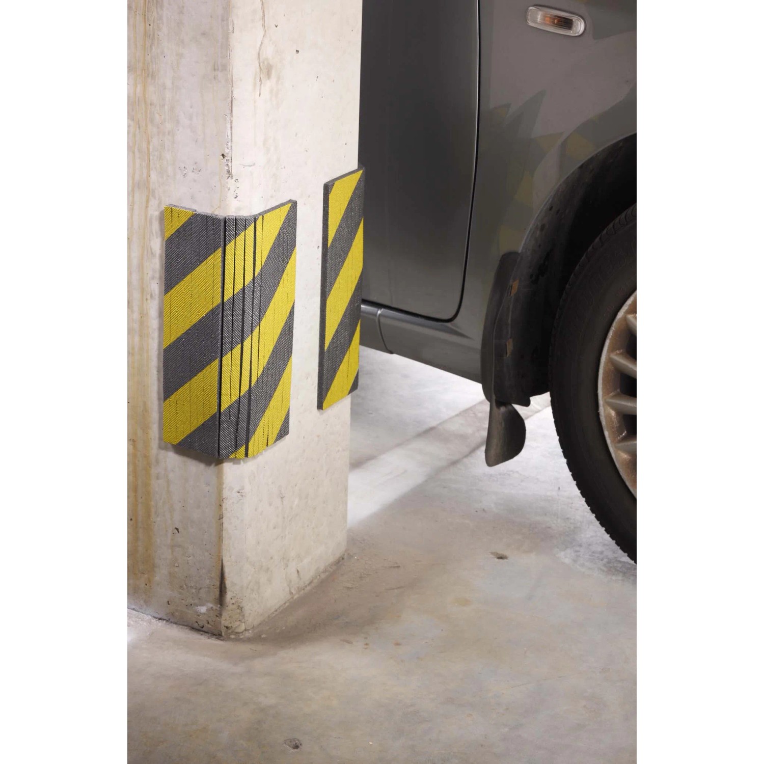 Protezione antiurto giallo-nera t.b.t. su una colonna di cemento in un garage.