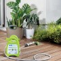 Unità di irrigazione t.b.t. verde e portatile con tubo e testina a spruzzo su terrazza in legno.