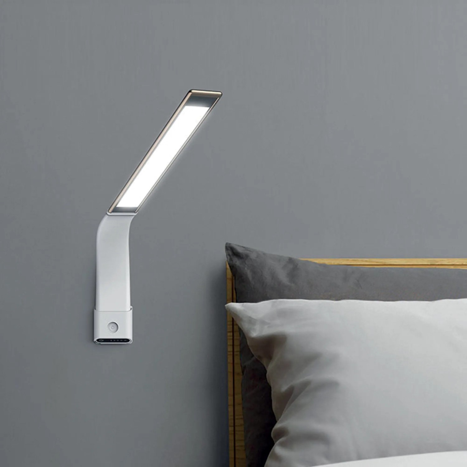 Moderna lampada da scrivania t.b.t. bianca montata su parete grigia accanto al letto.