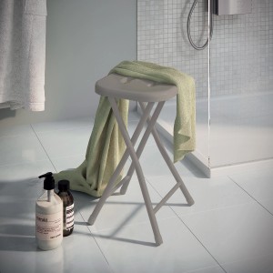 Sgabello da bagno pieghevole grigio con asciugamano in bagno.