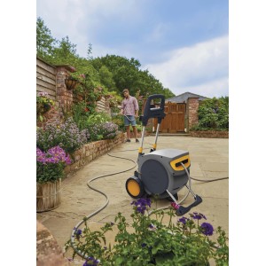 Avvolgitubo grigio con dettagli gialli in giardino, uomo che innaffia i fiori.