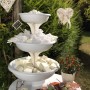 Ciotola per fiori decorativa a tre piani bianca con riempimento come decorazione da tavola.