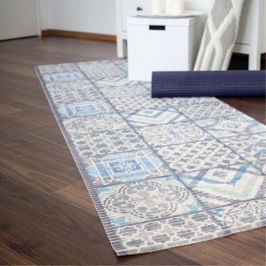 Tappeto da bagno t.b.t. con motivo a piastrelle blu-grigio su pavimento in legno.