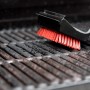 Spazzola per griglia Char-Broil Cool Clean Premium durante la pulizia di una griglia.
