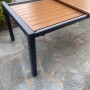 Tavolo da giardino allungabile con piano effetto legno e struttura in metallo scuro.