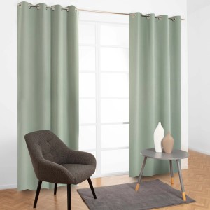 Tenda in tessuto verde t.b.t. con occhielli davanti alla finestra, abbinata a poltrona e tavolo.