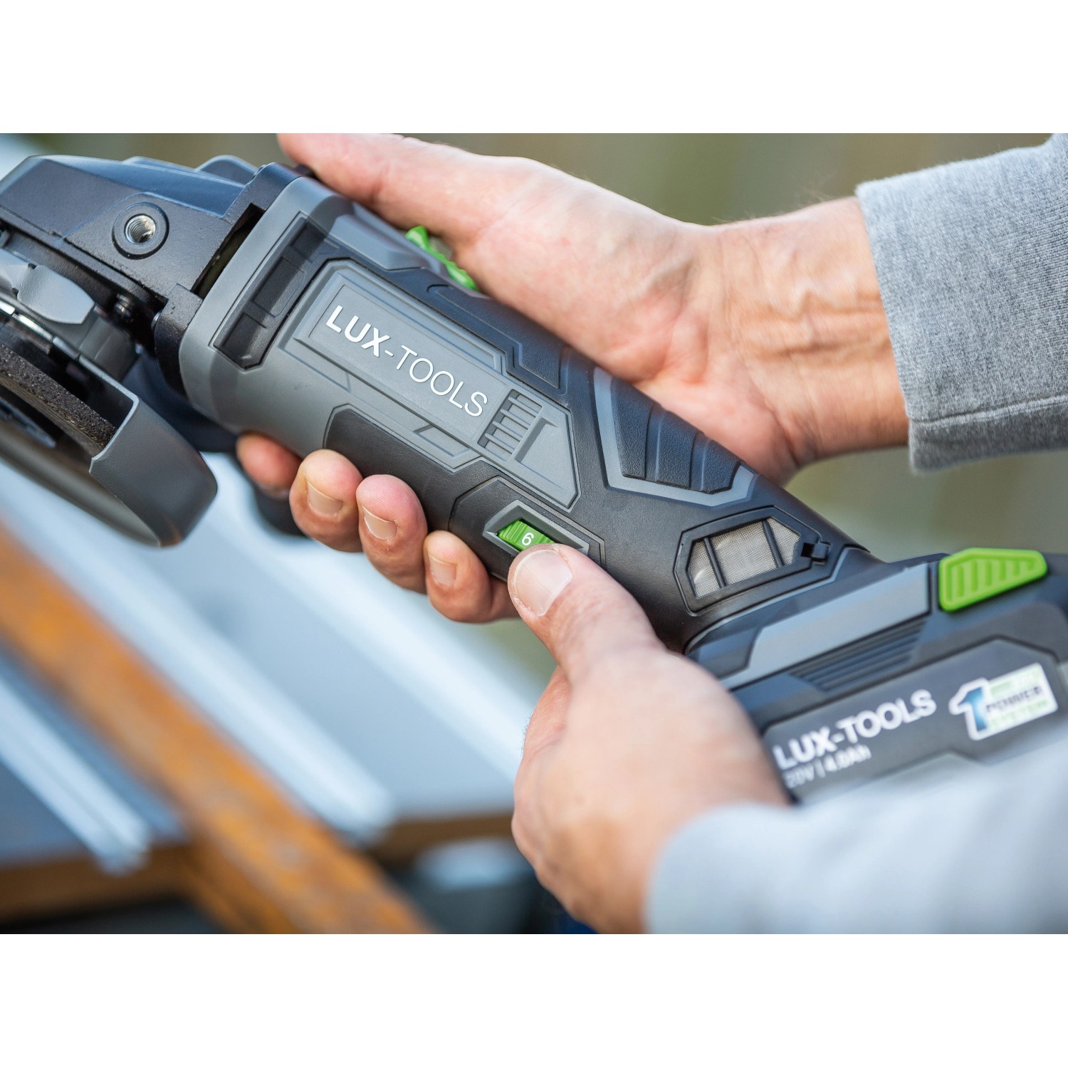 Smerigliatrice angolare a batteria LUX A-WS-20/115 in azione, mano che regola la velocità.