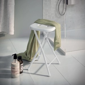 Sgabello da bagno pieghevole bianco con asciugamano in bagno.