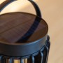 Lampada da tavolo solare nera Lutec Kozy con struttura a griglia e maniglia, Ø 13,7 cm.