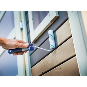 Mano che dipinge facciata in legno con rullo per velature LUX 12 cm. Rullo per velature e vernici.