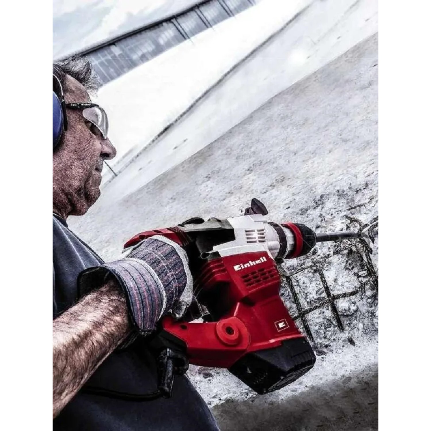 Martello demolitore rosso in azione durante la scalpellatura del cemento. Ideale per lavori di demolizione.