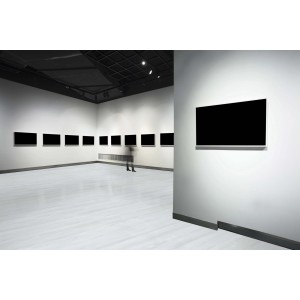 Sala espositiva con pavimenti vinilici e quadri neri alle pareti.