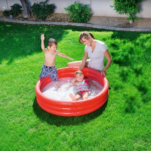 Piscina gonfiabile rossa con bambini e adulto che giocano in giardino.