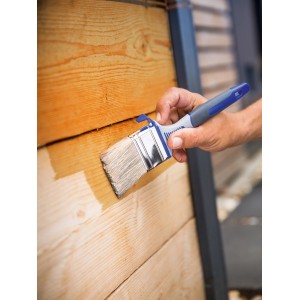Mano che impregna il legno con pennello piatto LUX 60mm. Pennello con serbatoio per maggiore assorbimento di vernice.