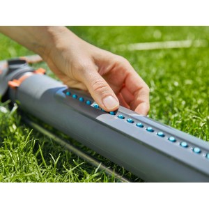 Gardena AquaZoom S irrigatore oscillante in uso: mano regola gli ugelli per un'irrigazione precisa del prato.