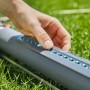 Gardena AquaZoom S irrigatore oscillante in uso: mano regola gli ugelli per un'irrigazione precisa del prato.