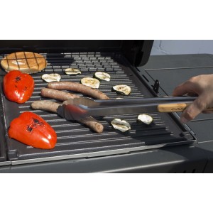 Pinze per barbecue su griglia con salsiccia, peperoni e zucchine. Accessori per barbecue.