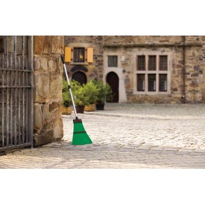 Scopa da esterno con manico telescopico, setole verdi e manico argentato, su pavimentazione in pietra.