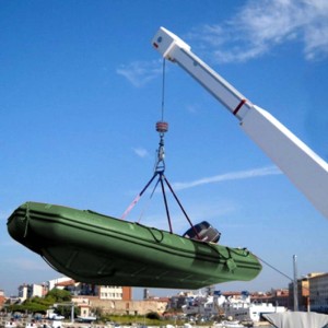 Gommone verde appeso a una gru con t.b.t. Tenditore e Cinghie di fissaggio.