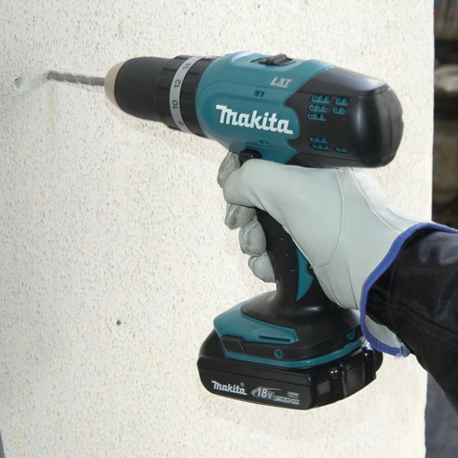 Trapano avvitatore a percussione a batteria Makita DHP453RFE durante la foratura nel muro.