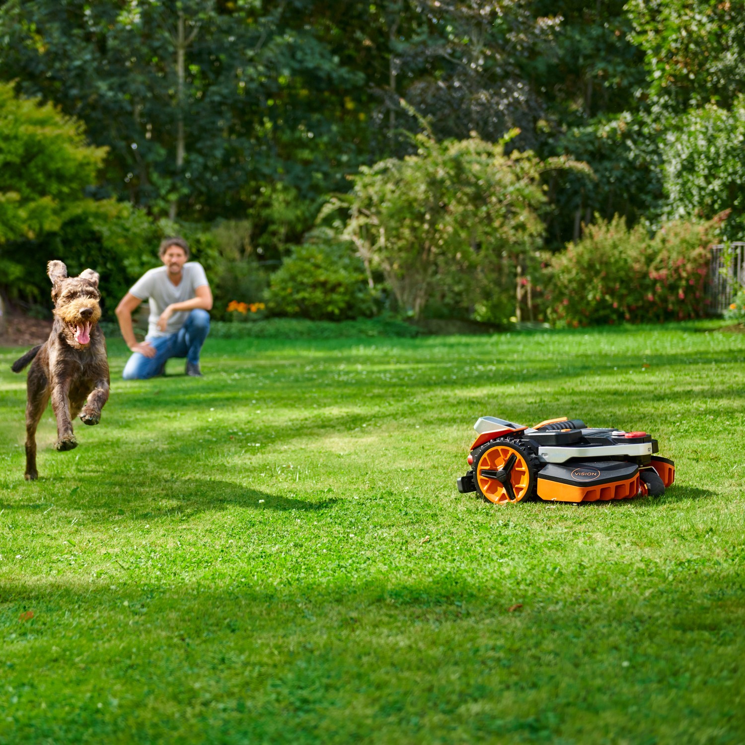 Robot rasaerba Worx Landroid Vision M800 in azione con cane e uomo in giardino.
