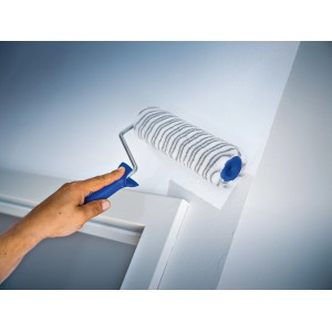 Rullo a dispersione LUX 18 cm mentre dipinge una parete, rullo per pittura con pelo corto a righe grigie.