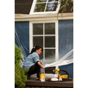 Donna che copre la finestra con la pellicola Tesa Easy Cover Universal. Materiali di copertura per la ristrutturazione.