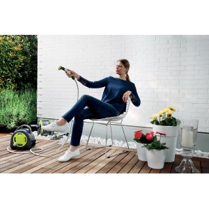 Donna che utilizza l'avvolgitubo t.b.t. con tubo da giardino e pistola a spruzzo per l'irrigazione del giardino.