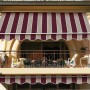 Tenda da sole t.b.t. a strisce bordeaux e beige sul balcone.