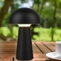 Lampada da tavolo LED Reality Lennon nera a forma di fungo, Ø 13,6 cm, su tavolo di legno in giardino.